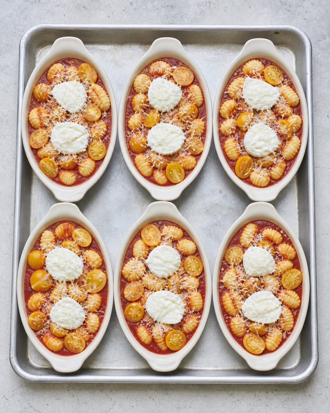 Præcis seks ens portionsfade rummer gnocchi, tæt rød sauce, kun gyldne tomater og præcis to adskilte mozzarellaøer i hvert fad