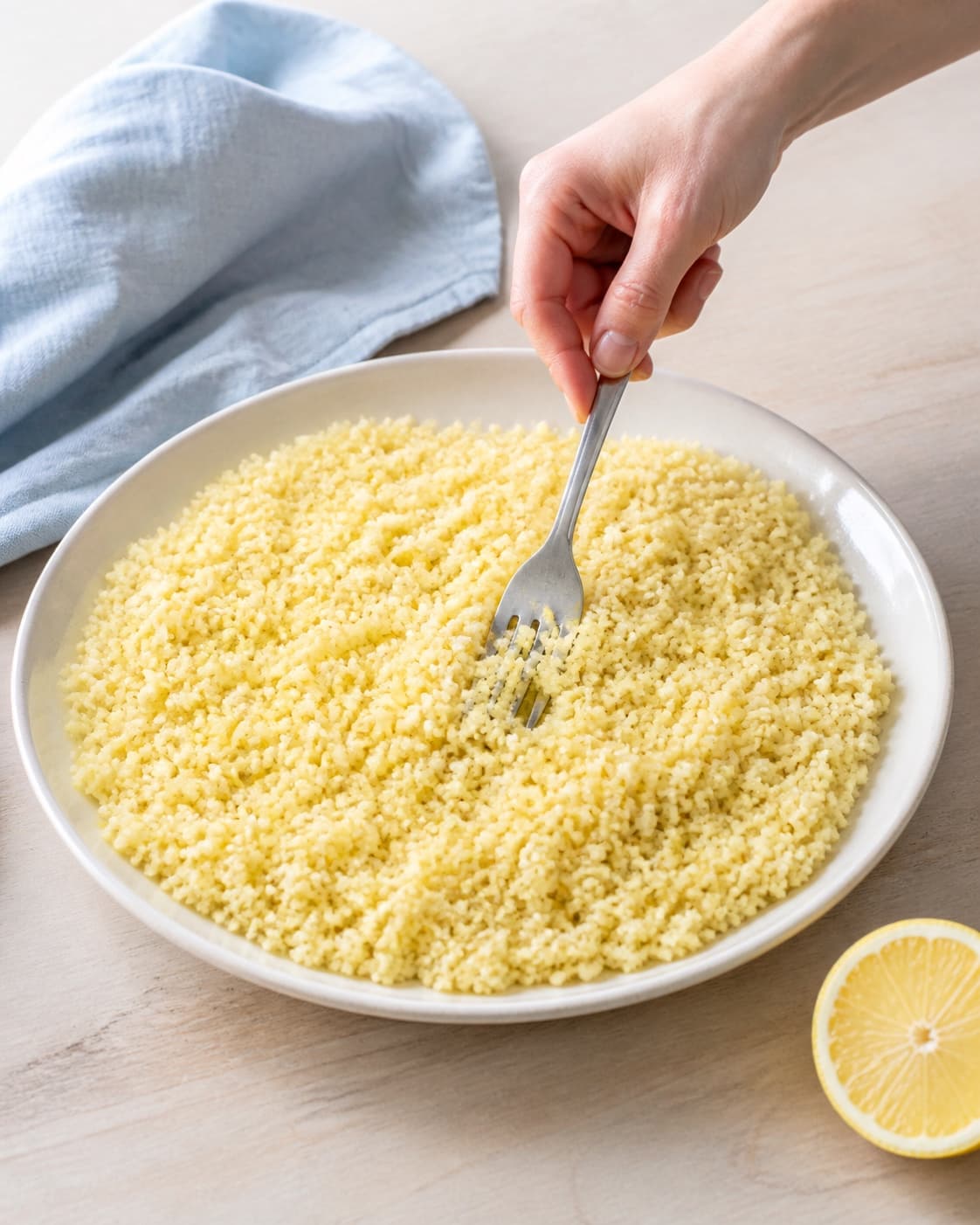 Lys citroncouscous løsnes med en gaffel i et lavt fad, så hvert korn ligger separat uden tør kerne, klumper eller væske i bunden