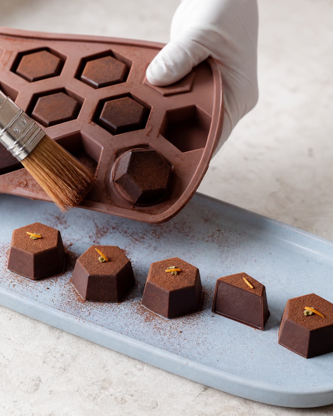 Kolde facetterede chokoladetrøfler udformes og børstes fri for overskydende kakao før appelsinskal og kardemomme