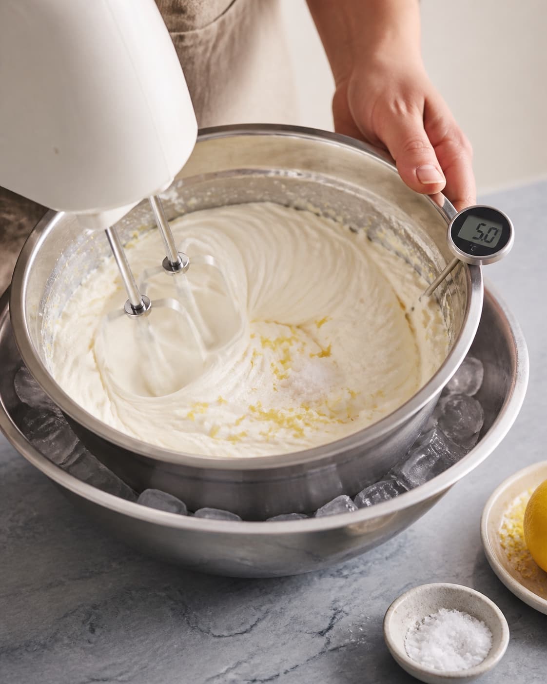 Drænet ricotta piskes kort med kold fløde og citron i skål over is, til hvide luftige spor holder ved 5 °C