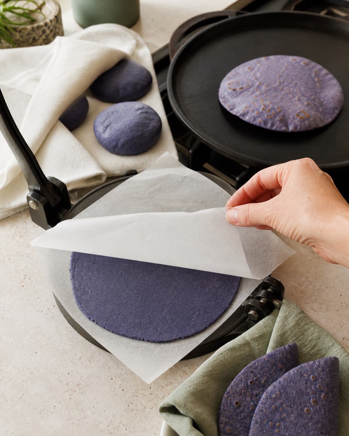 Blød blå masadej presses til en tynd jævn tortilla, bages tørt med små brune pletter og pakkes varm i klæde