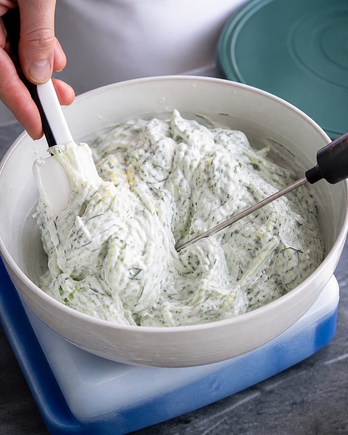 Den kolde tzatziki foldes tæt og ske-fast med tydelige agurkstrimler, dild og citronskal uden klar væske langs kanten