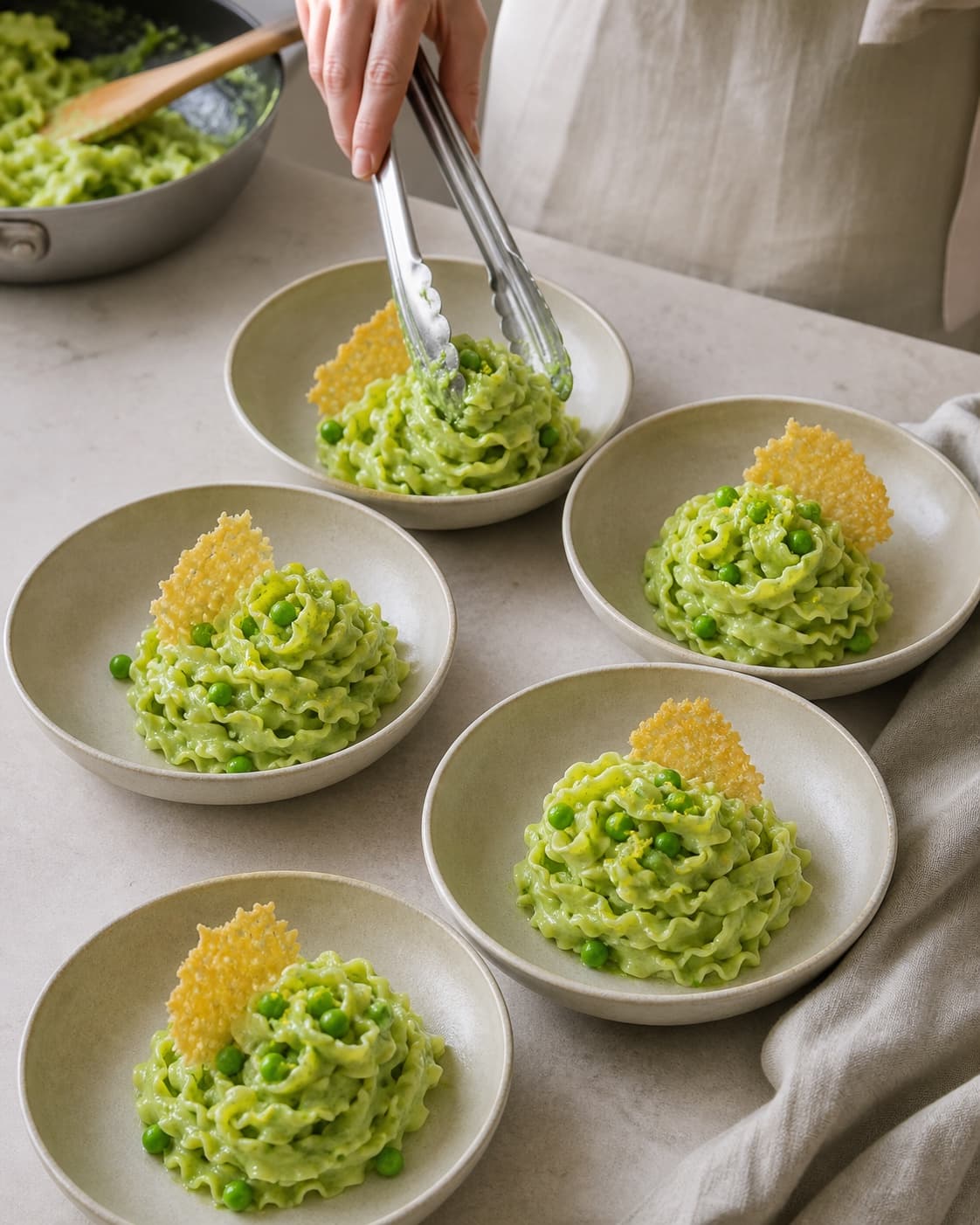 Præcis fem løse mafaldinereder er blankt dækket af silkeblød lysegrøn ærtecreme med hele ærter, citron og sprød parmesanflage