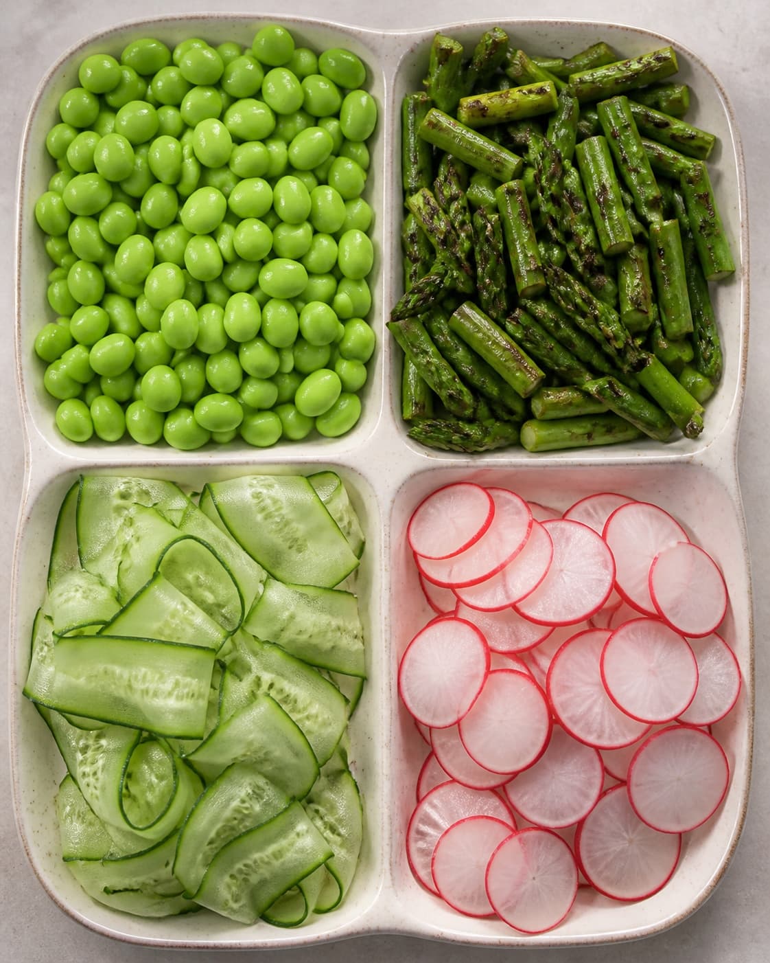 Edamame, grillet asparges, tørre agurkebånd og radiseskiver ligger i fire helt adskilte teksturzoner