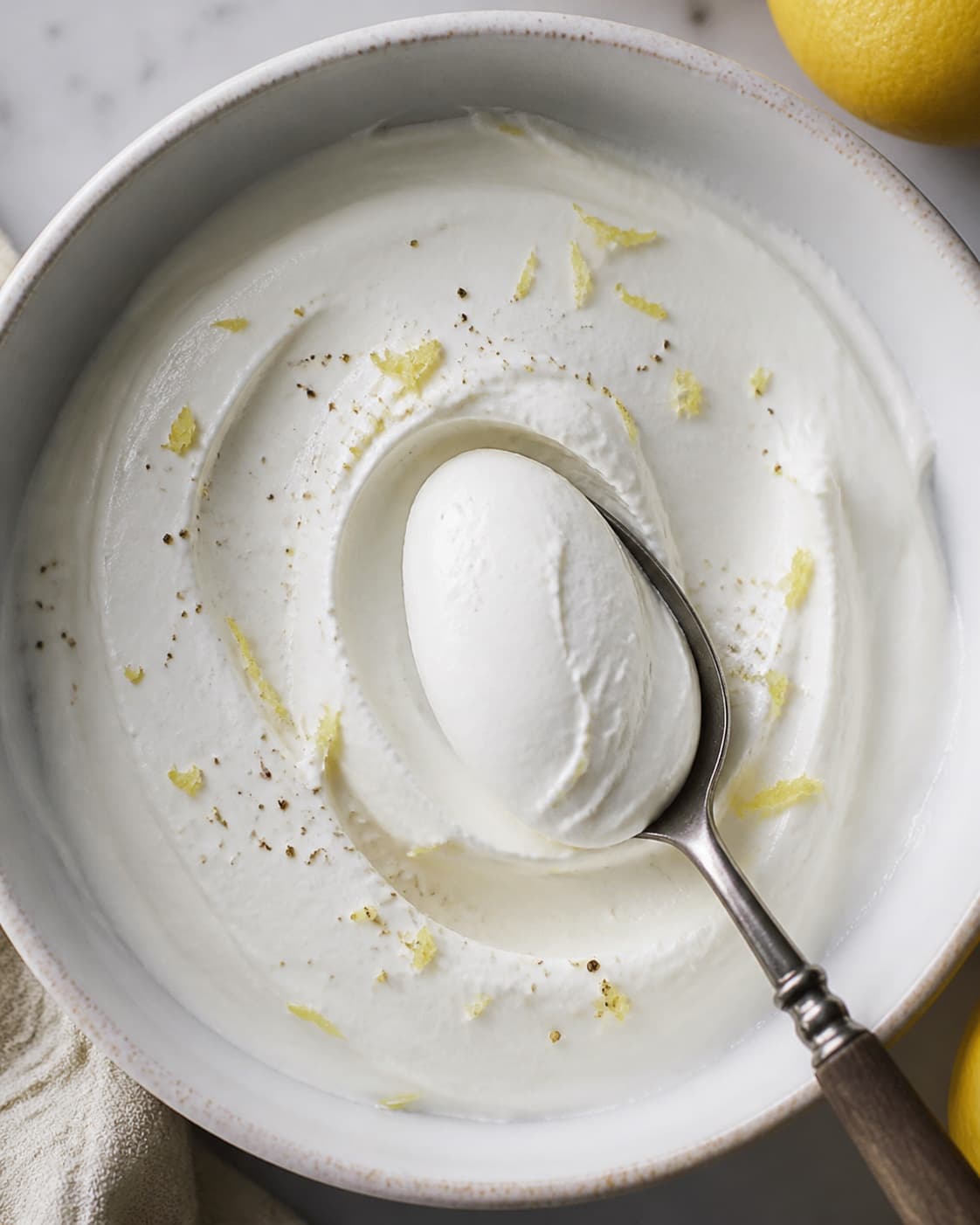 Kold glat fetacreme løftes som en fast hvid quenelle med citronskal og peber uden ostekorn eller valle