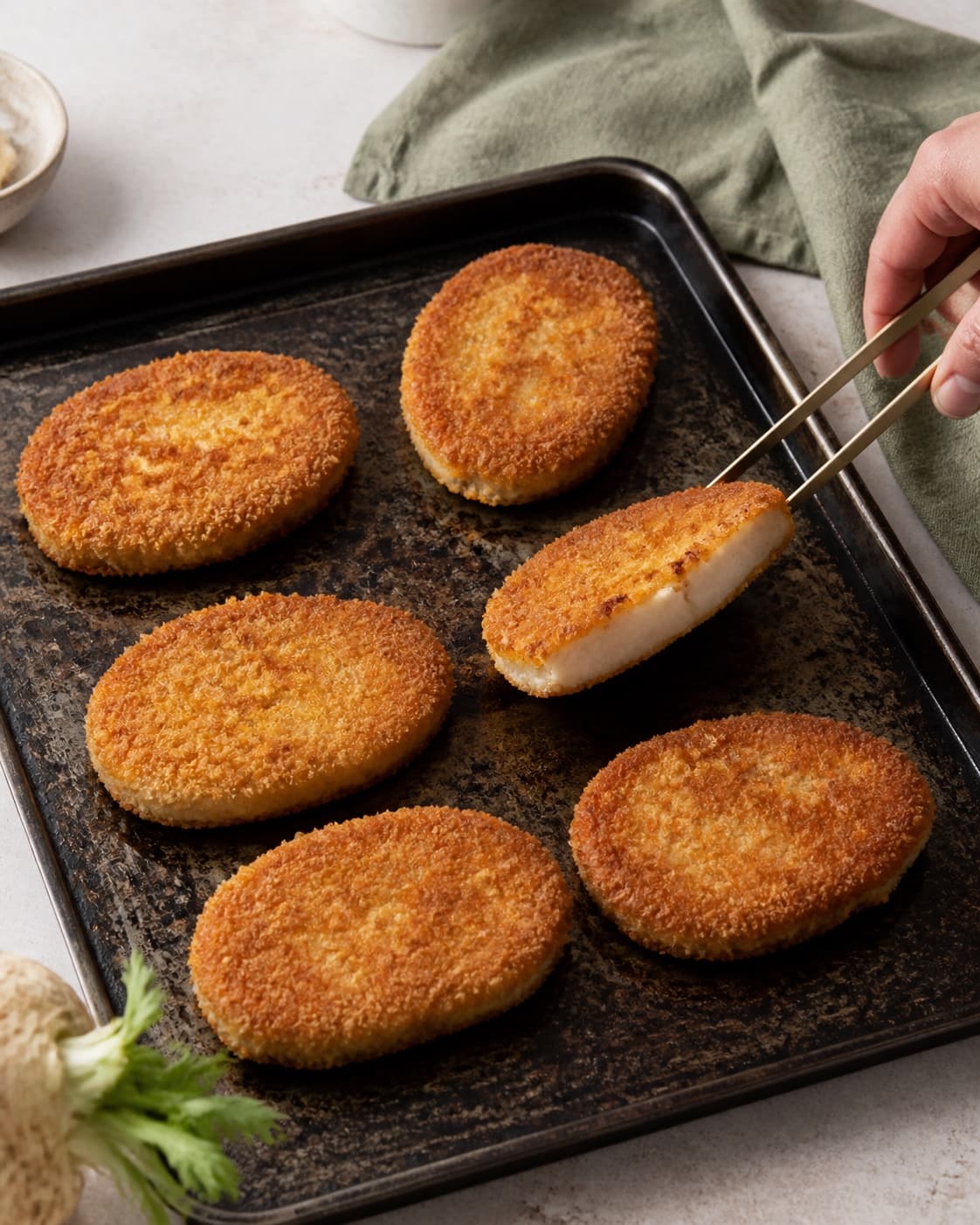 Seks ovale sellerischnitzler har dybt gylden sprød panko, og én vendes for at vise den lyse møre midte