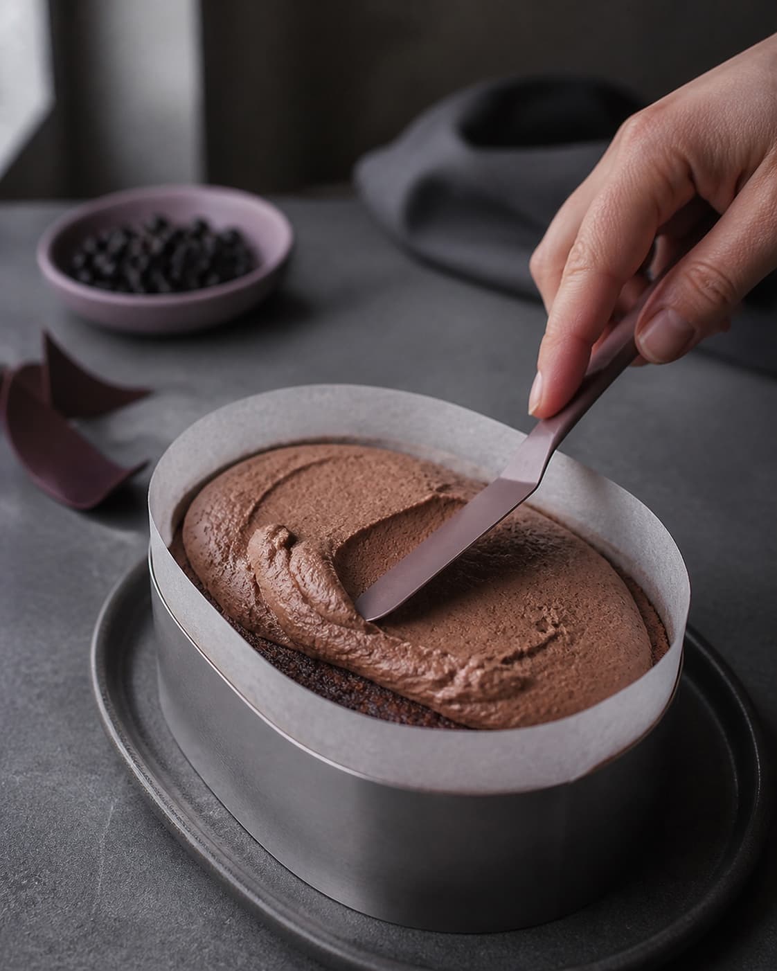 Luftig chokolademousse fordeles jævnt over den kolde ovale chokoladebund med paletkniv