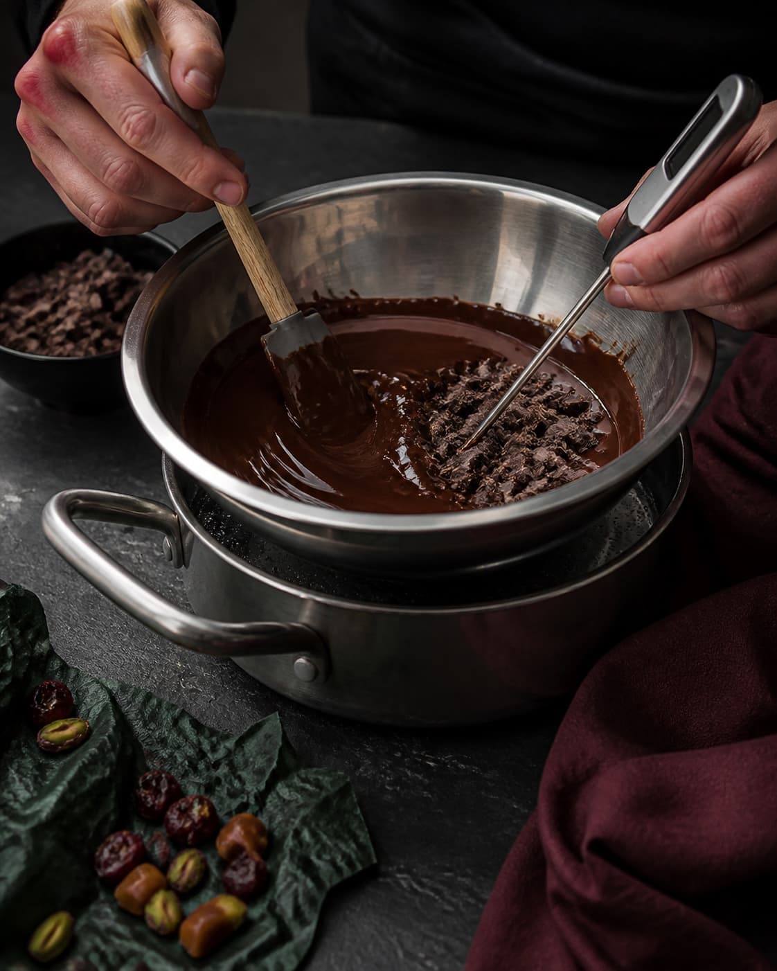 Blank mørk chokolade røres i en helt tør skål over vandbad, mens tør temperaturføler og reserveret chokolade bruges til temperering