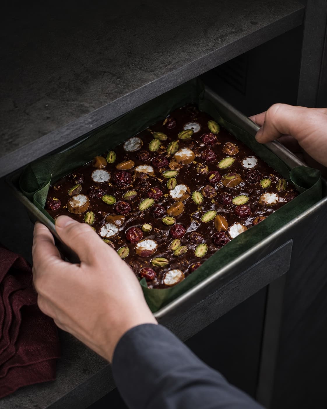 Rocky road-masse med pistacie, tranebær, karamel og skumfidus er bredt i grønforet form og sættes på en kølig tør hylde