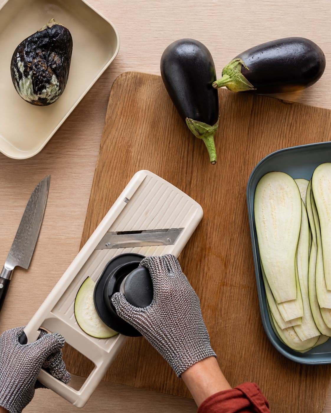 Vasket aubergine skæres sikkert på langs med mandolin og håndbeskytter, mens muggen frugt er kasseret separat