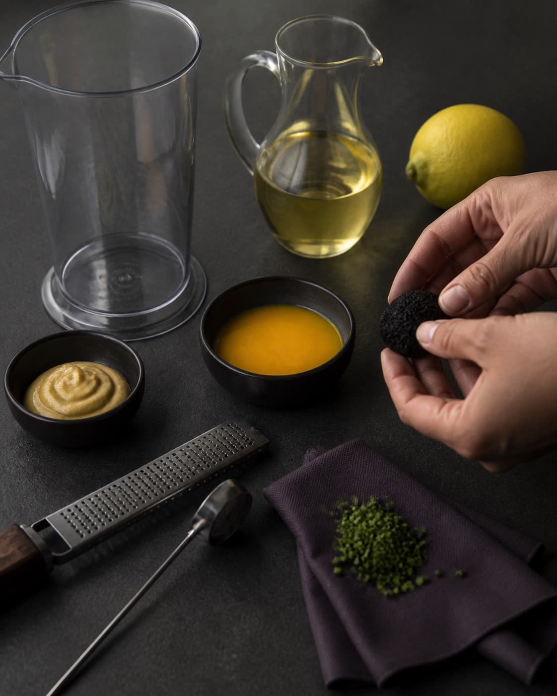 To hænder kontrollerer en frisk sort trøffel ved en ren kold station med pasteuriseret blomme, citron, olie og tørt udstyr