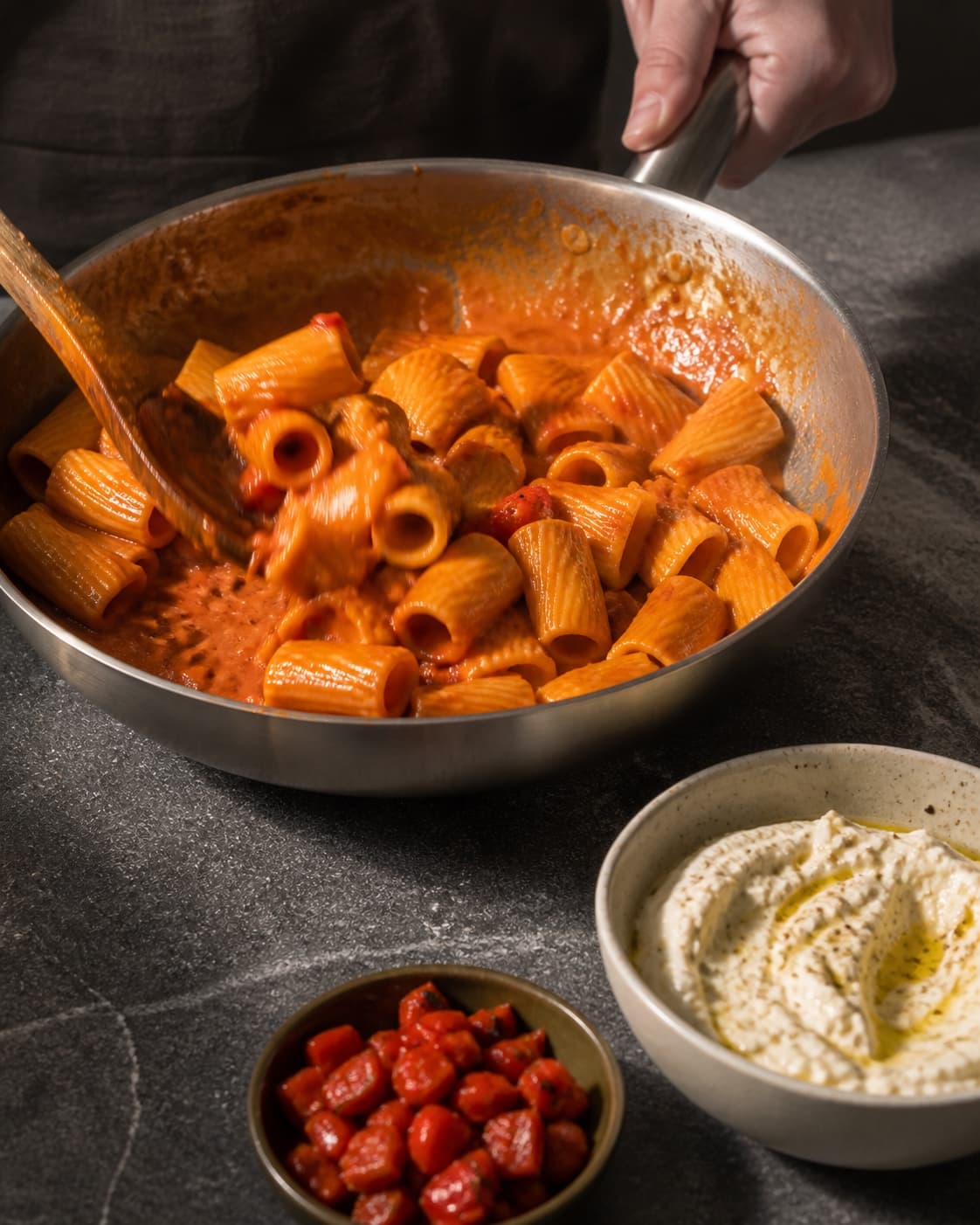To hænder vender rigatoni energisk i blank sauce, mens pisket citronricotta og pebertern holdes separat til sen anretning