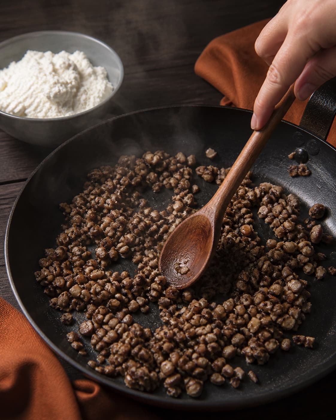 Finthakkede svampe steges brune og helt tørre i bred pande, ricotta står separat