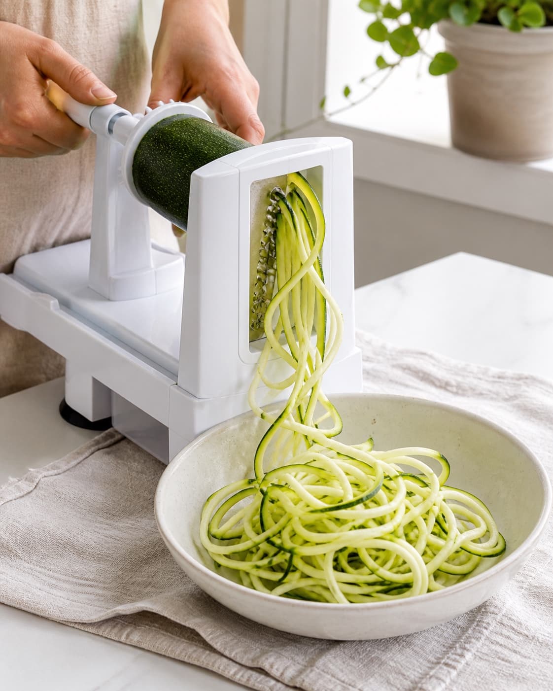 Fast grøn squash køres gennem spiralizer til lange tørre grøntsagsstrimler