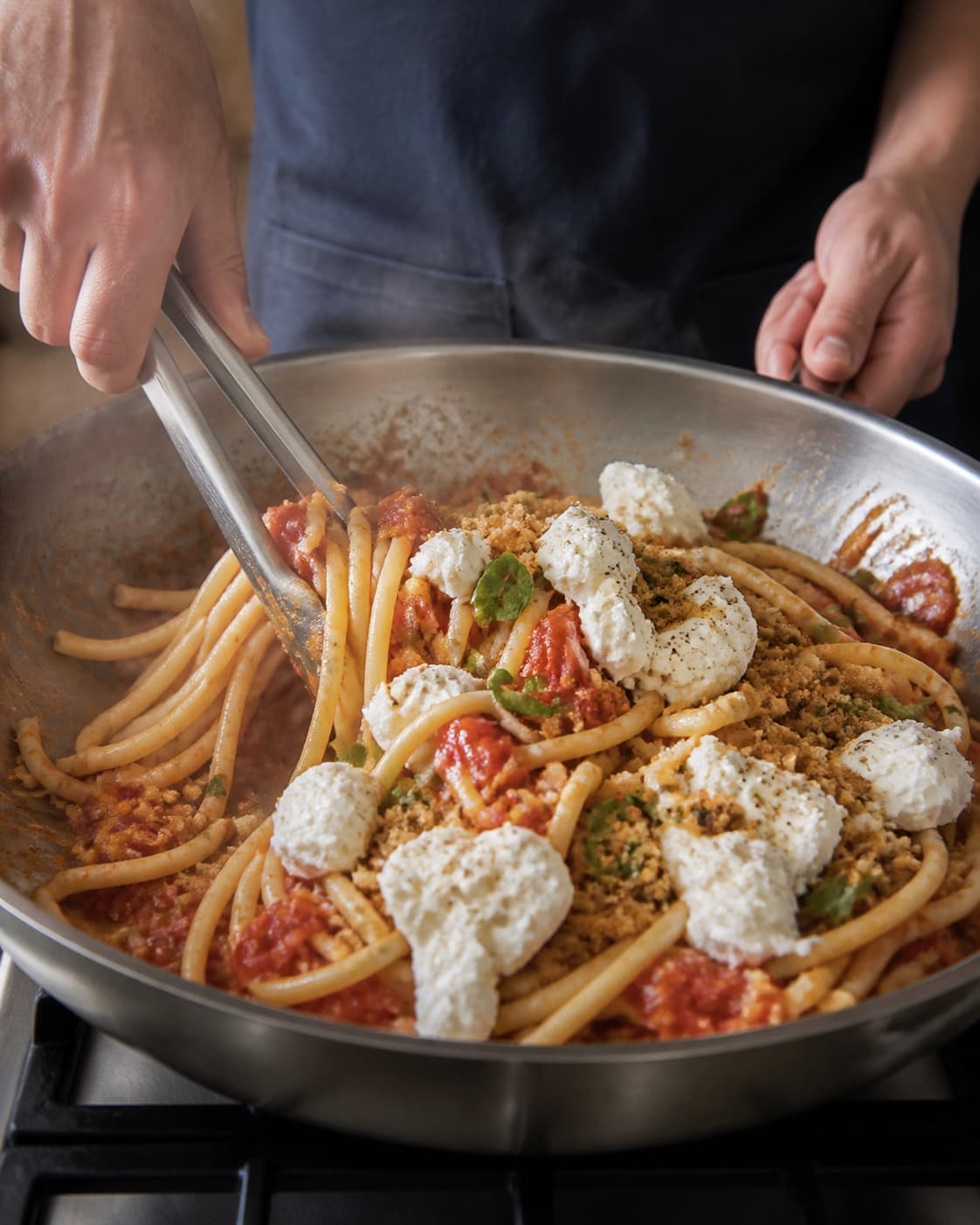 Bucatini vendes i tomatsauce og afsluttes væk fra varme med burrata og pangrattato