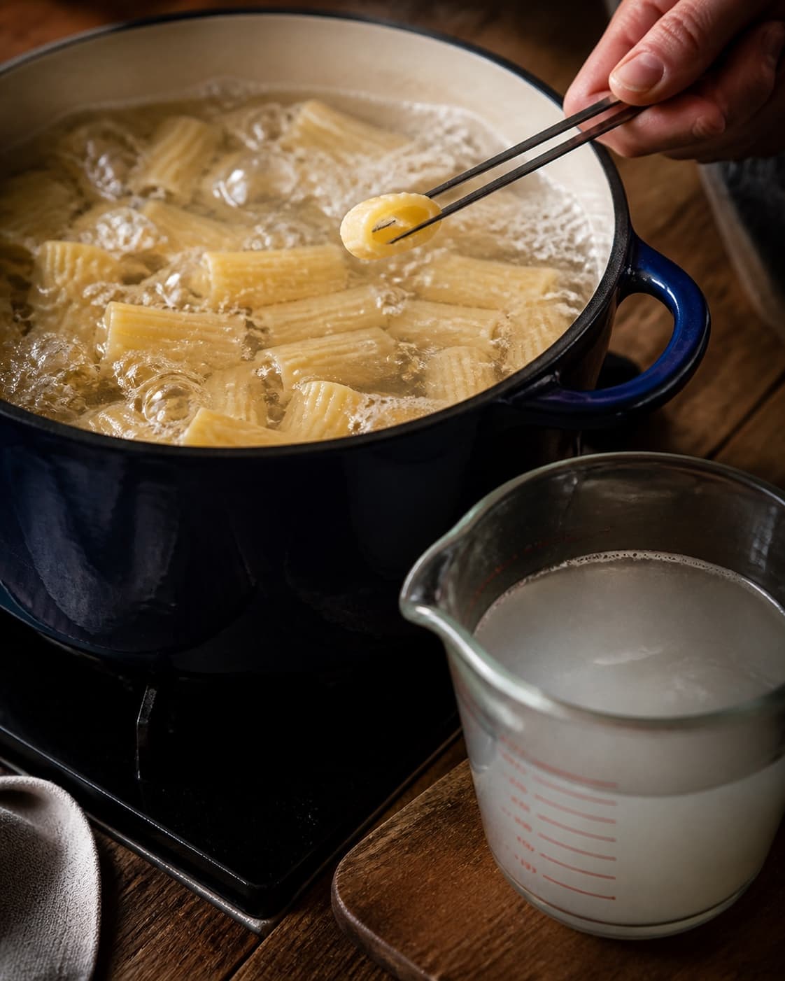 Rigatoni koges al dente, mens et rør kontrolleres og uklart pastavand gemmes
