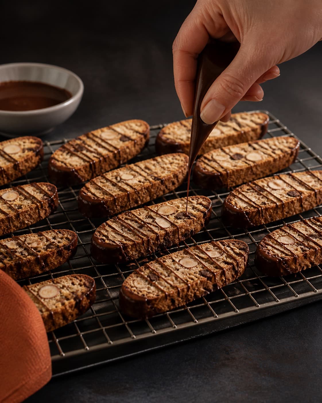 biscottistængerne hviler på rist før en ekstra tynd chokoladestreg tilføjes under tilberedningen af biscotti med mandel, chokolade og appelsinfennikel