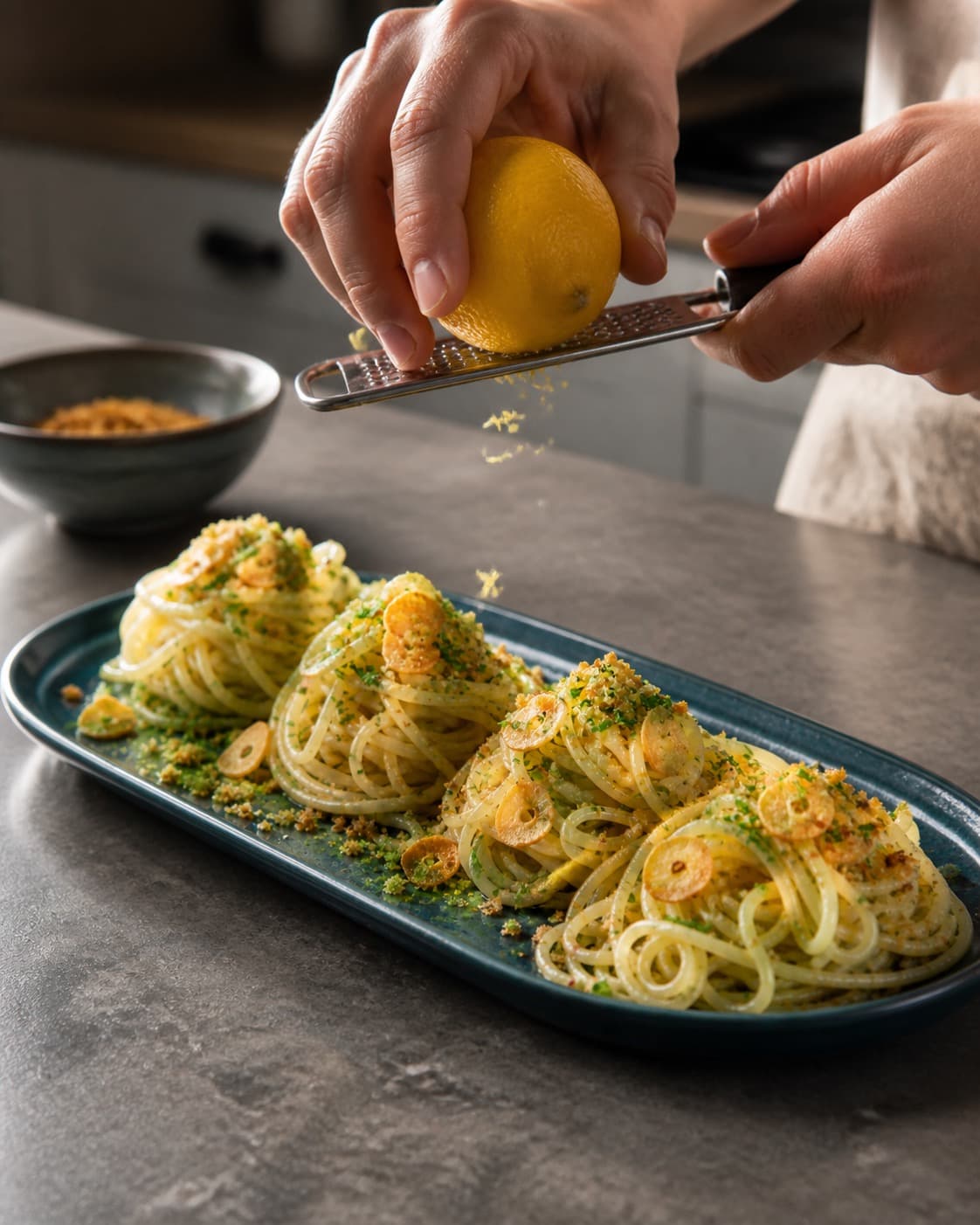 spaghetti aglio e olio får persille, citron og rugknas lige før servering under tilberedningen af spaghetti aglio e olio med ristet hvidløg og citron