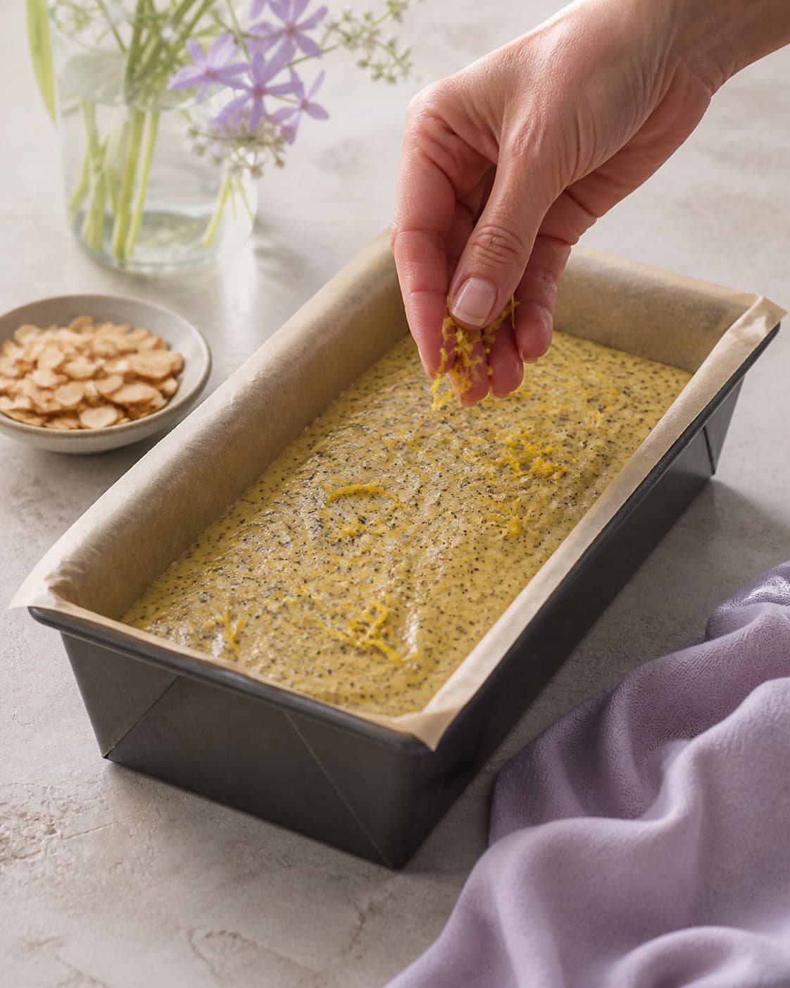 birkes og citronskal fordeles jævnt i den ubagte citronkagen under tilberedningen af citronkage med birkes, marcipan og skyrfrosting