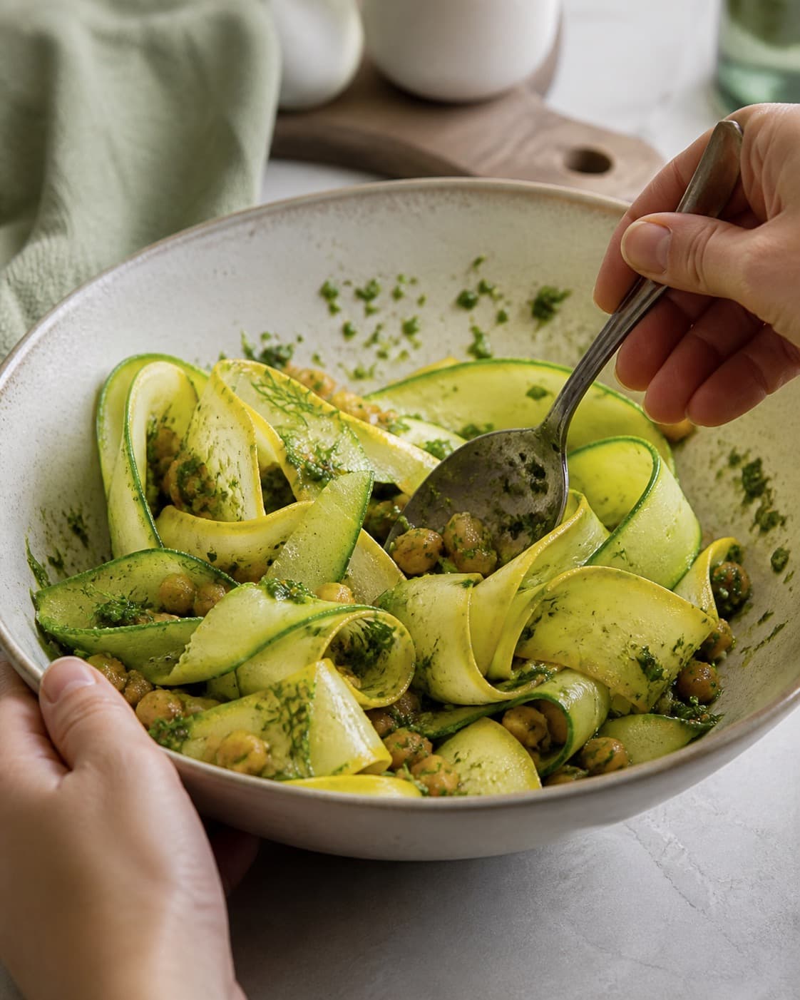 squashsalaten vendes nænsomt med basilikum-persillepestoen under tilberedningen af squashsalat med urtepesto, ricotta og pinjekerner