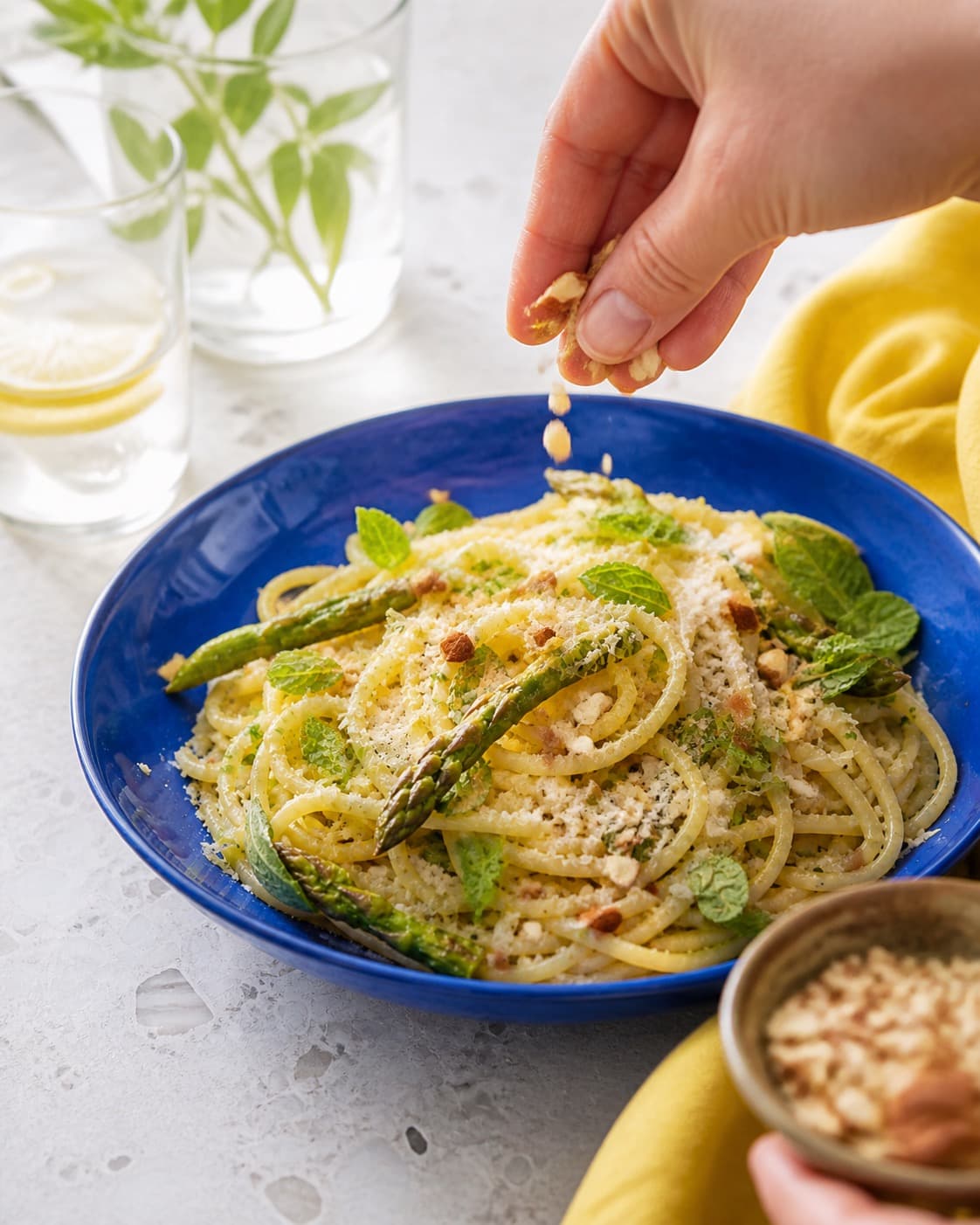 citronpastaen får mynte, pecorino og ristede mandler lige før servering under tilberedningen af citronpasta med asparges, mynte og pecorino