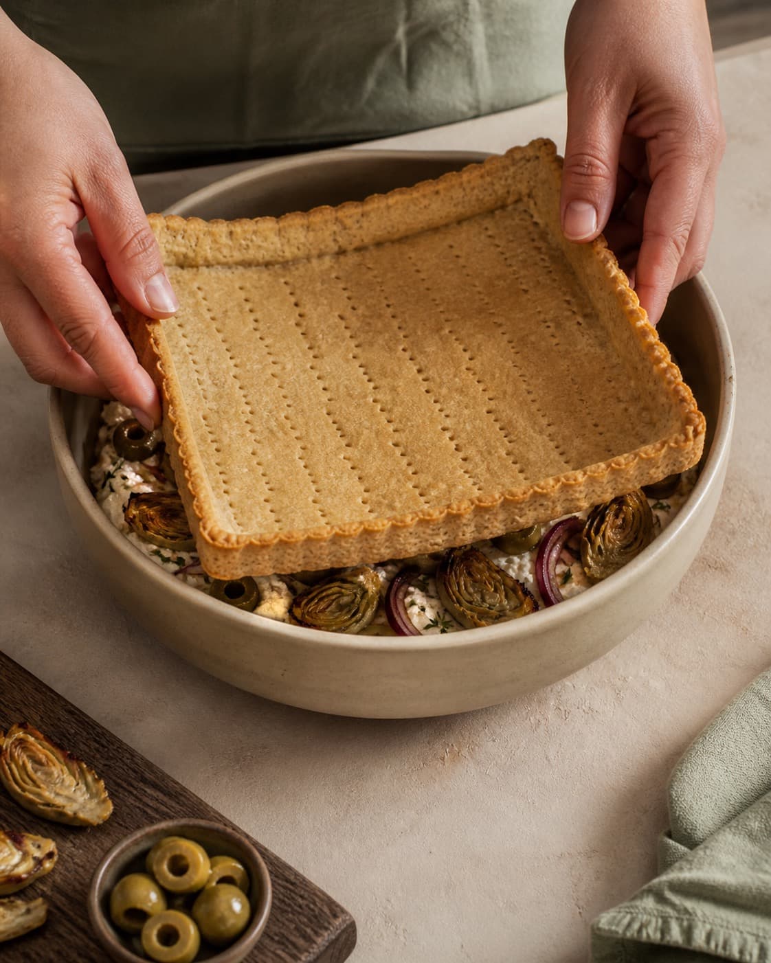 den blindbagte smørbund samles nænsomt til artiskoktærten i en røreskål under tilberedningen af artiskoktærte med ricotta, citron og oliven
