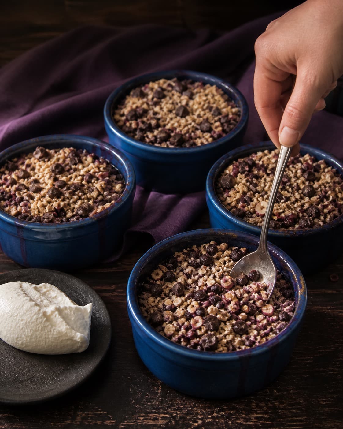 solbær, vanilje og chokolade fordeles jævnt i den ubagte solbærcrumblen under tilberedningen af solbærcrumble med chokolade, hasselnød og rug