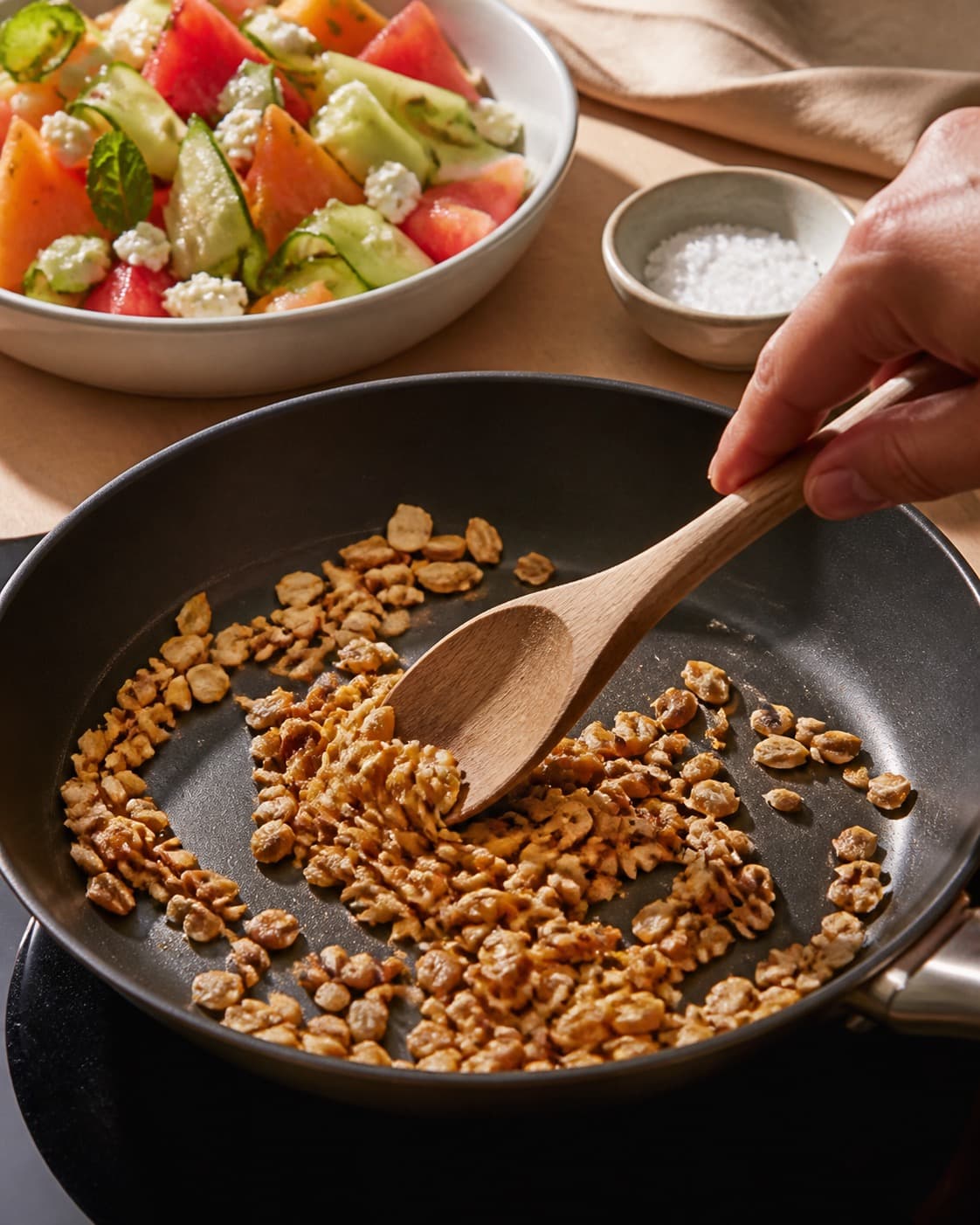 Sprødt tilbehør ristes gyldent til melonsalaten under tilberedningen af melonsalat med chili, mynte, feta og græskarkerner