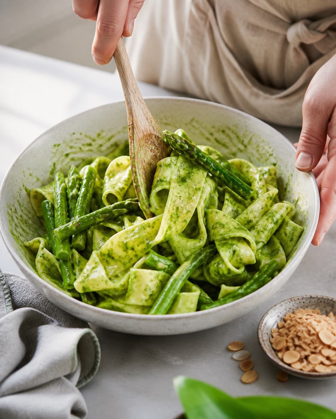Pasta svinges blank med ramsløgscreme og asparges under tilberedningen af pappardelle med ramsløgscreme, asparges og mandler