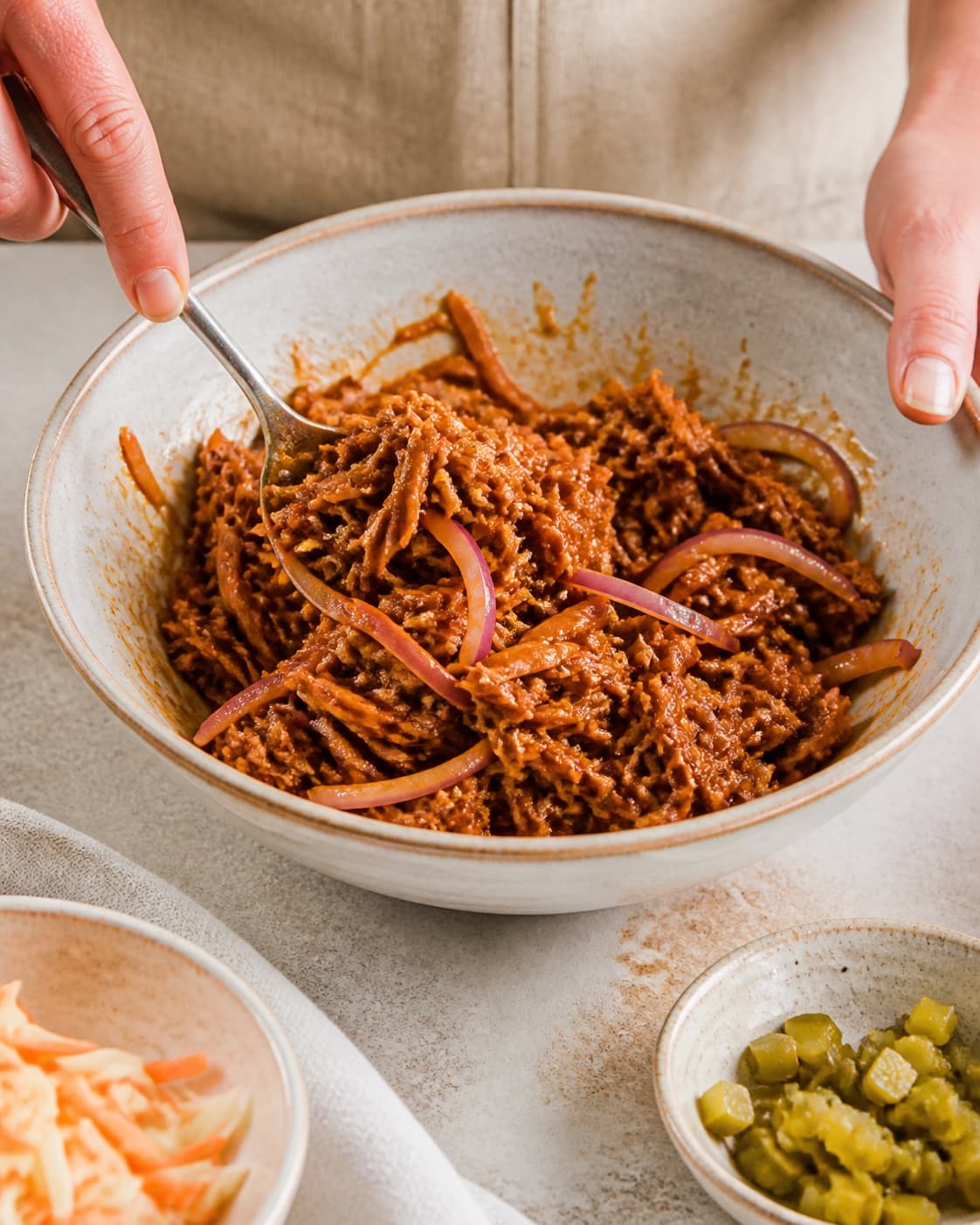 rødløg og gennemvarmet pulled pork blandes til en fast masse til pulled pork-hotdoggen under tilberedningen af pulled pork-hotdog med syltet kål og sprøde løg