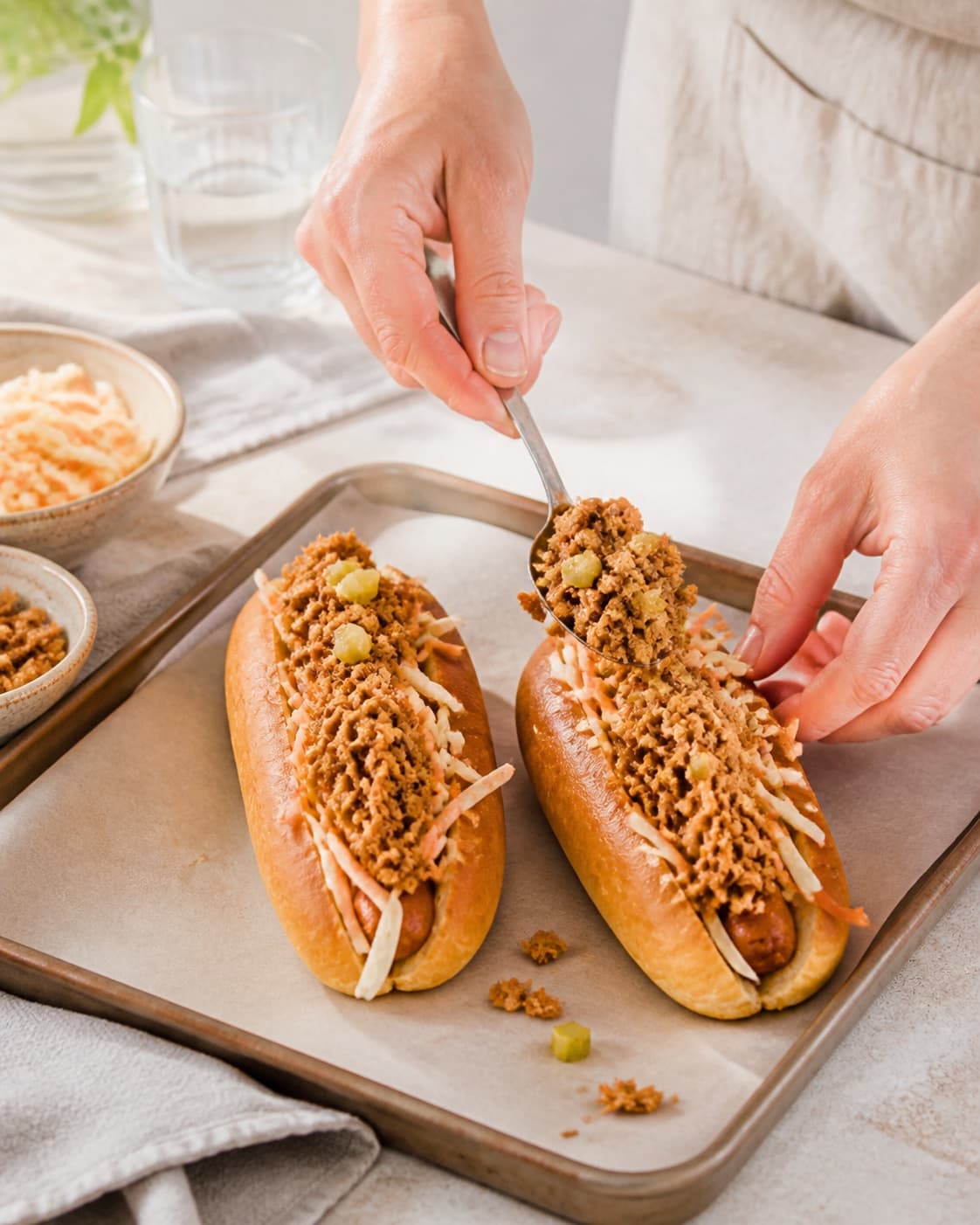 pulled pork-hotdoggen formes i ens emner på en plade under tilberedningen af pulled pork-hotdog med syltet kål og sprøde løg