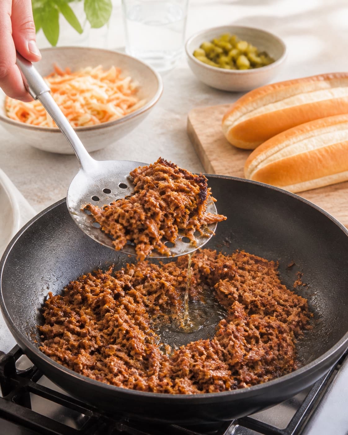 pulled pork-hotdoggen afdrypper sprød før syltet kål, æble og sennep under tilberedningen af pulled pork-hotdog med syltet kål og sprøde løg