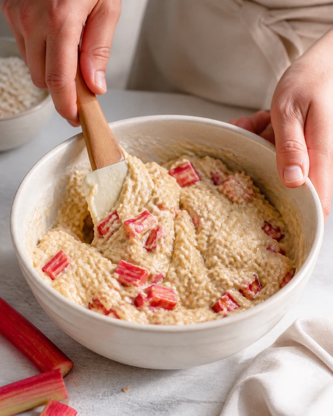 kærnemælksdejen med marcipan samles nænsomt til rabarbermuffinsene under tilberedningen af rabarbermuffins med marcipan, hvid chokolade og havrecrumble