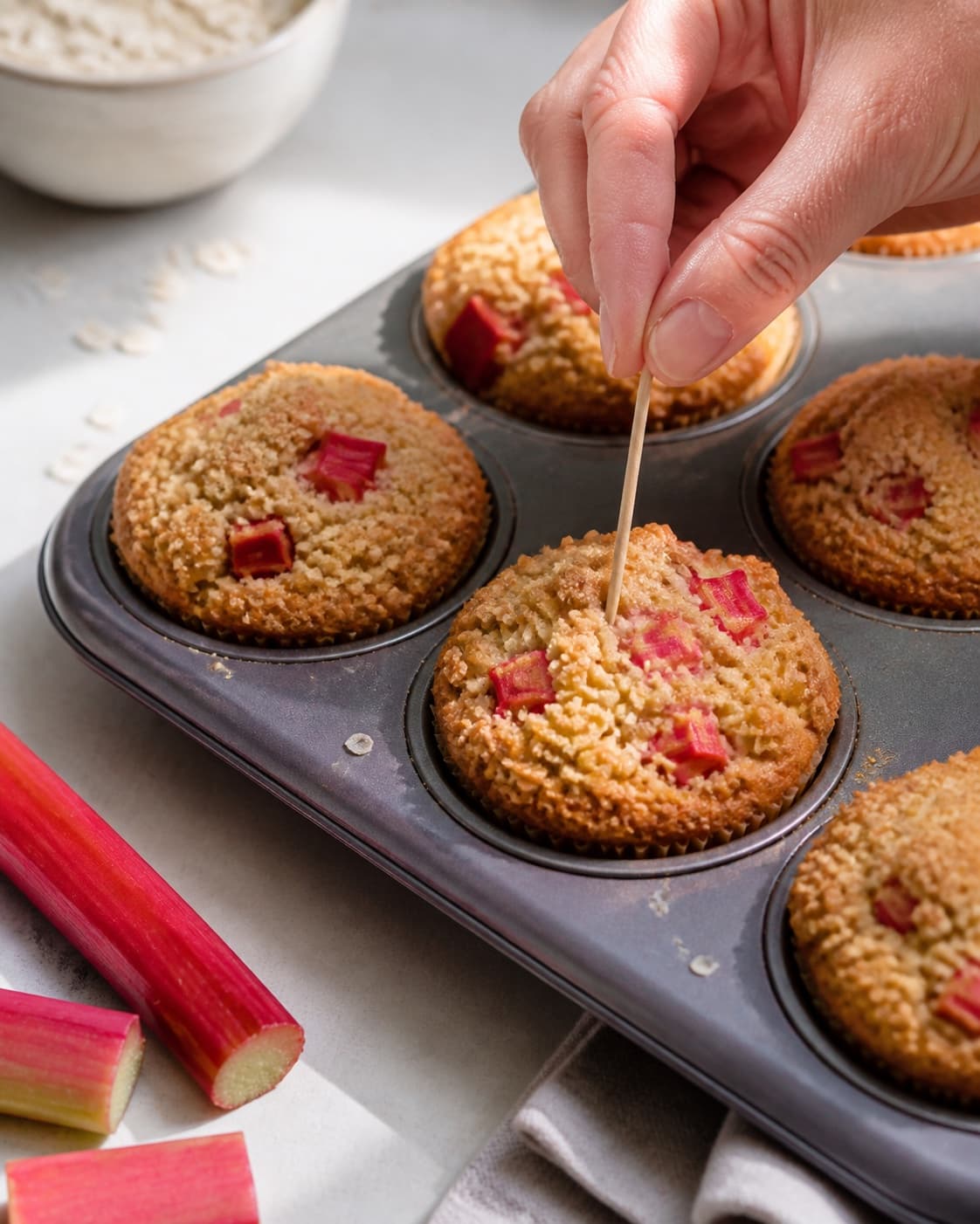 rabarbermuffinsene bager gylden med synligt fast centrum under tilberedningen af rabarbermuffins med marcipan, hvid chokolade og havrecrumble