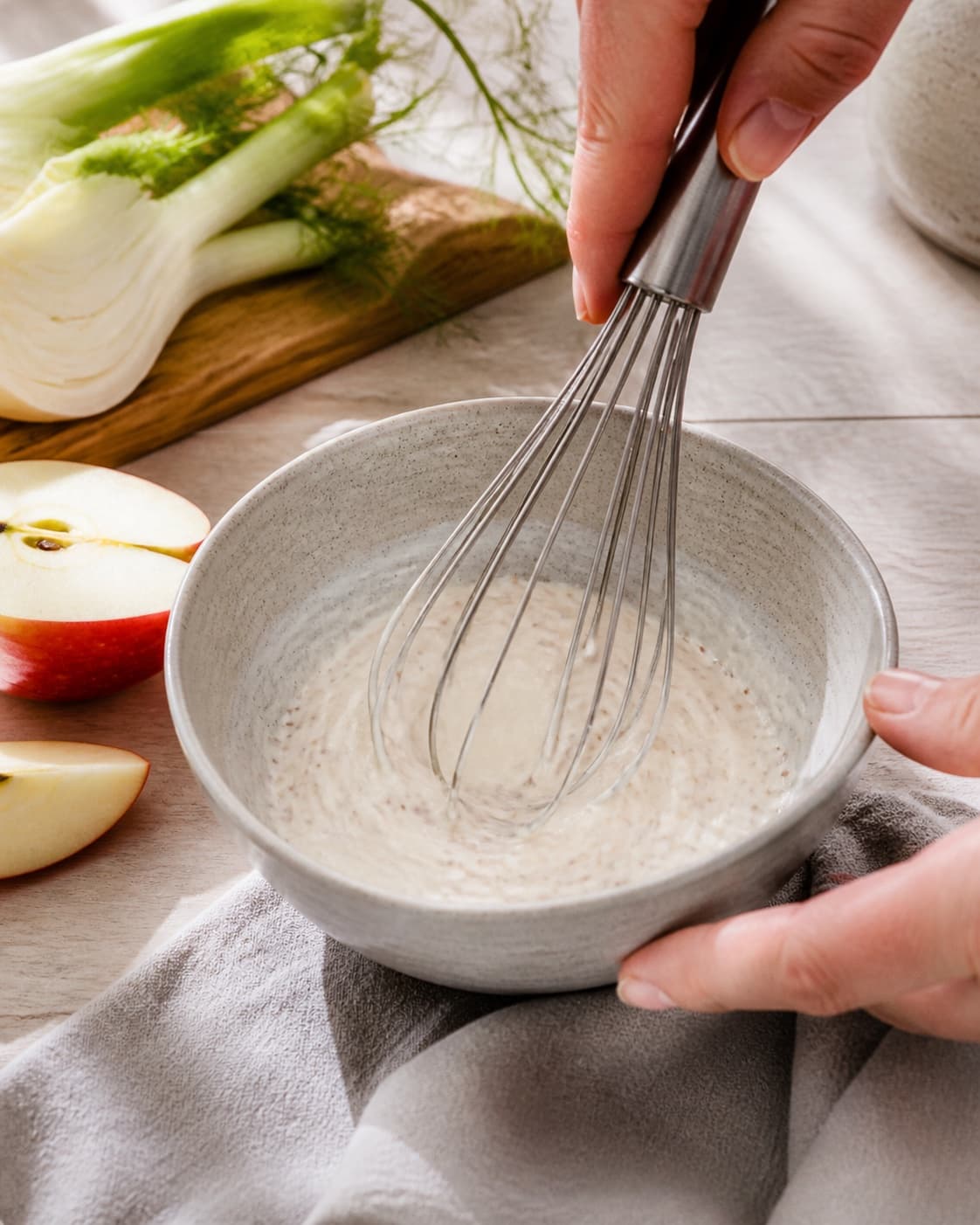 skyr-sennepsdressingen piskes blank i en lille skål under tilberedningen af kålslaw med æble, fennikel og sennepsdressing