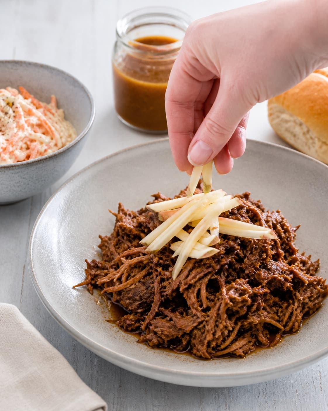 pulled porken anrettes med reduceret sky og syrligt æble under tilberedningen af langtidsstegt pulled pork med æblemost og fennikelfrø