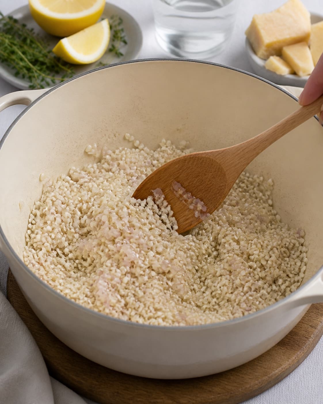 skalotteløg og risottoris svedes blankt i en tykbundet gryde under tilberedningen af sæsonrisotto med citron, parmesan og urteolie
