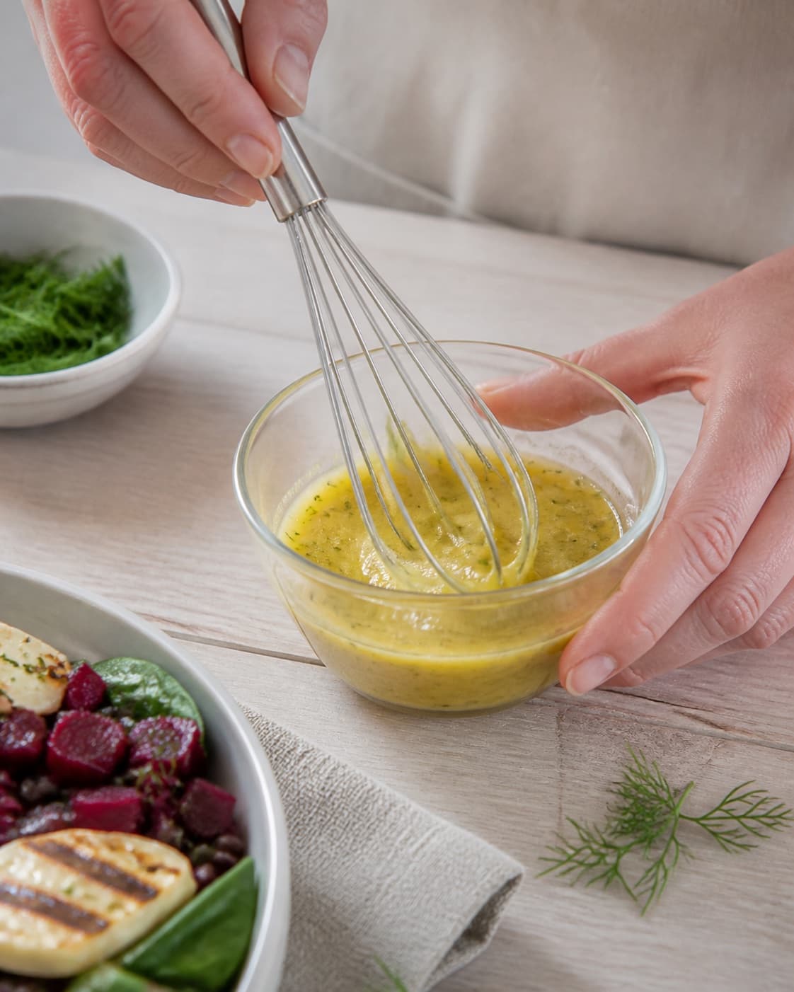 dild-sennepsdressingen piskes blank i en lille skål under tilberedningen af belugalinsesalat med grillost, rødbede og dild