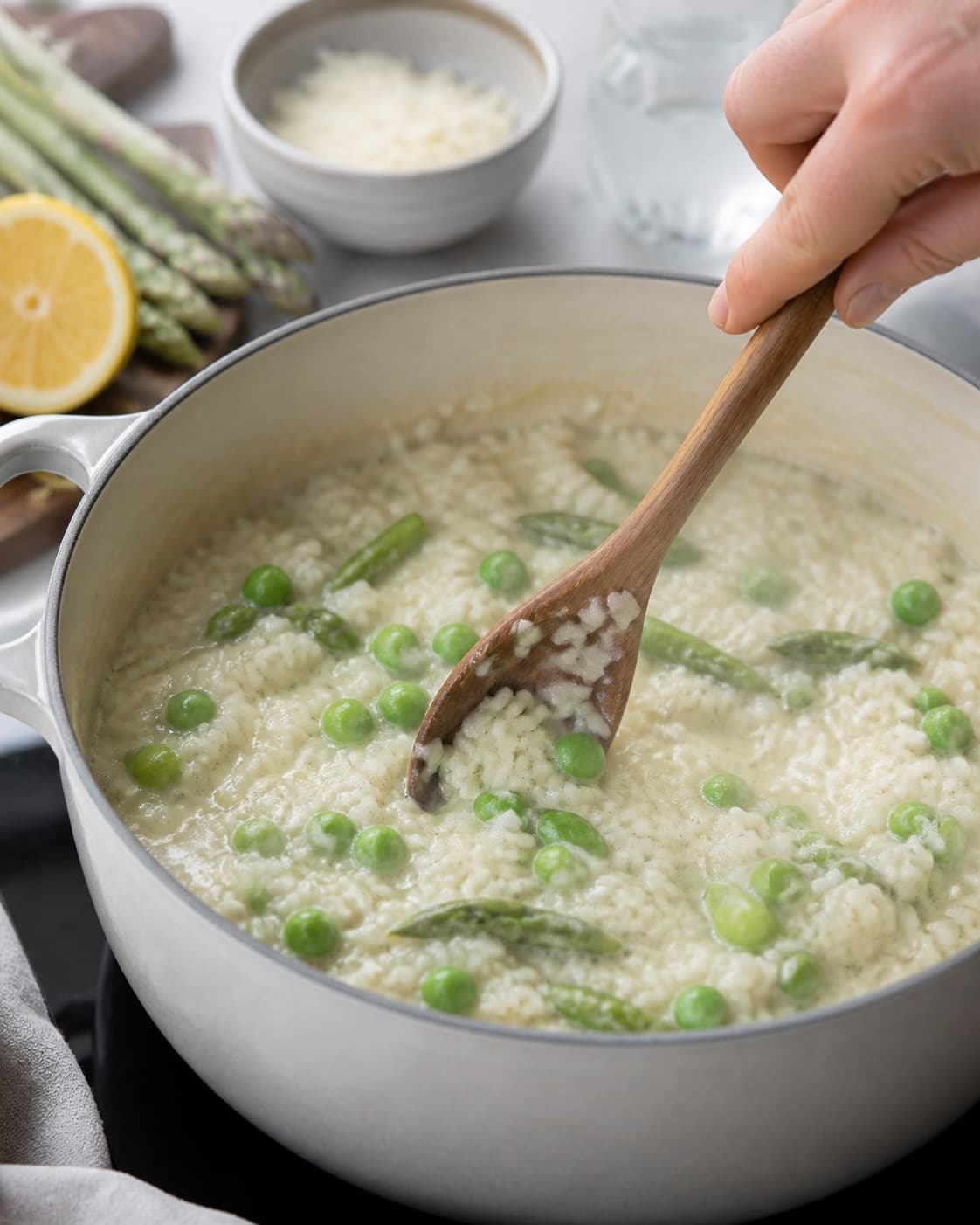 aspargesrisottoen simrer roligt med små bobler under tilberedningen af aspargesrisotto med citron, ærter og pecorino