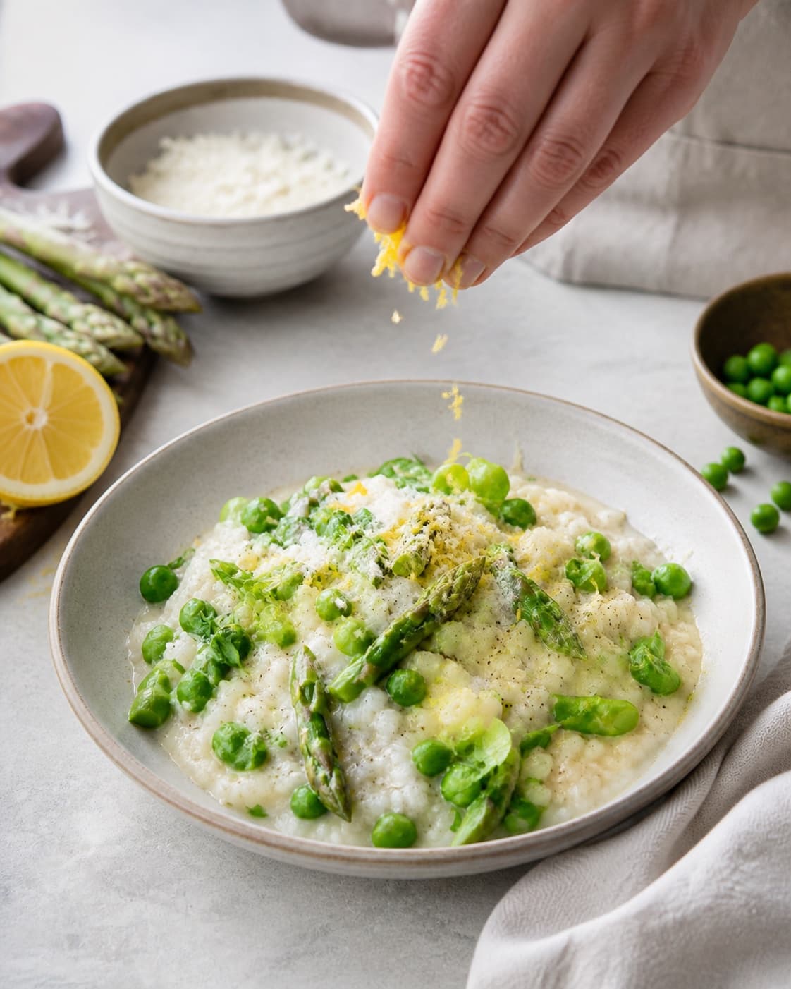 aspargesrisottoen afsluttes med aspargestoppe, ærter, pecorino og citron under tilberedningen af aspargesrisotto med citron, ærter og pecorino