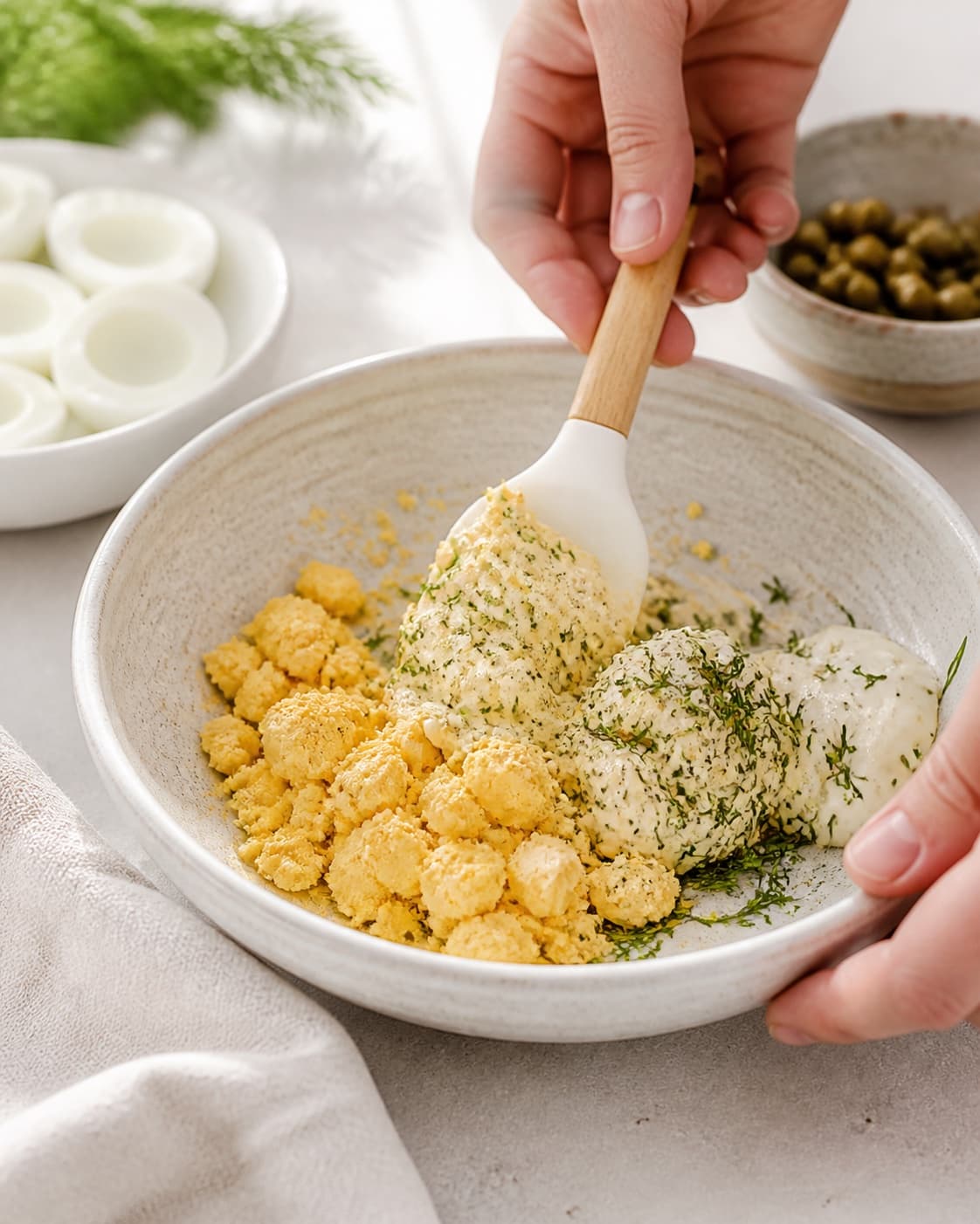 hårdkogte æggeblommer og dildcreme blandes til en fast masse til de fyldte æg under tilberedningen af fyldte æg med dild, sennep og sprøde kapers