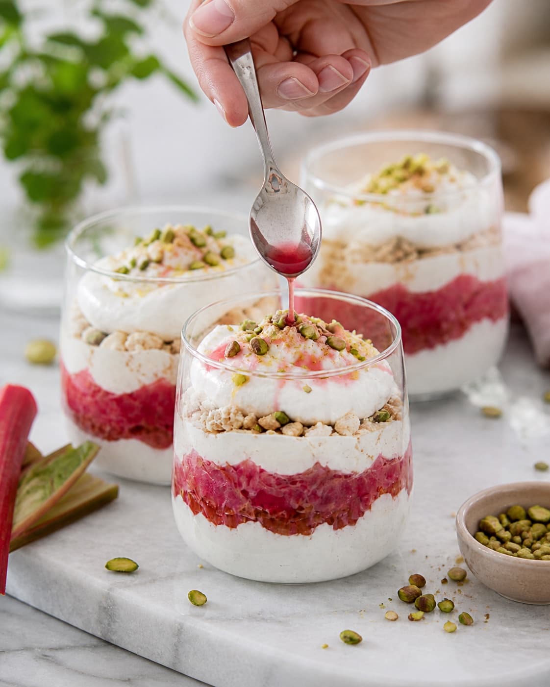 rabarbertriflien afsluttes kold med pistacie, rabarbersaft og citronskal under tilberedningen af rabarbertrifli med makroner, vaniljeskum og pistacie