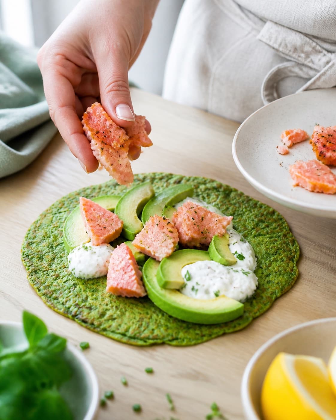 spinatpandekagerne afdrypper sprød før varmrøget laks, avocado og dilddressing under tilberedningen af spinatpandekager med varmrøget laks og avocado
