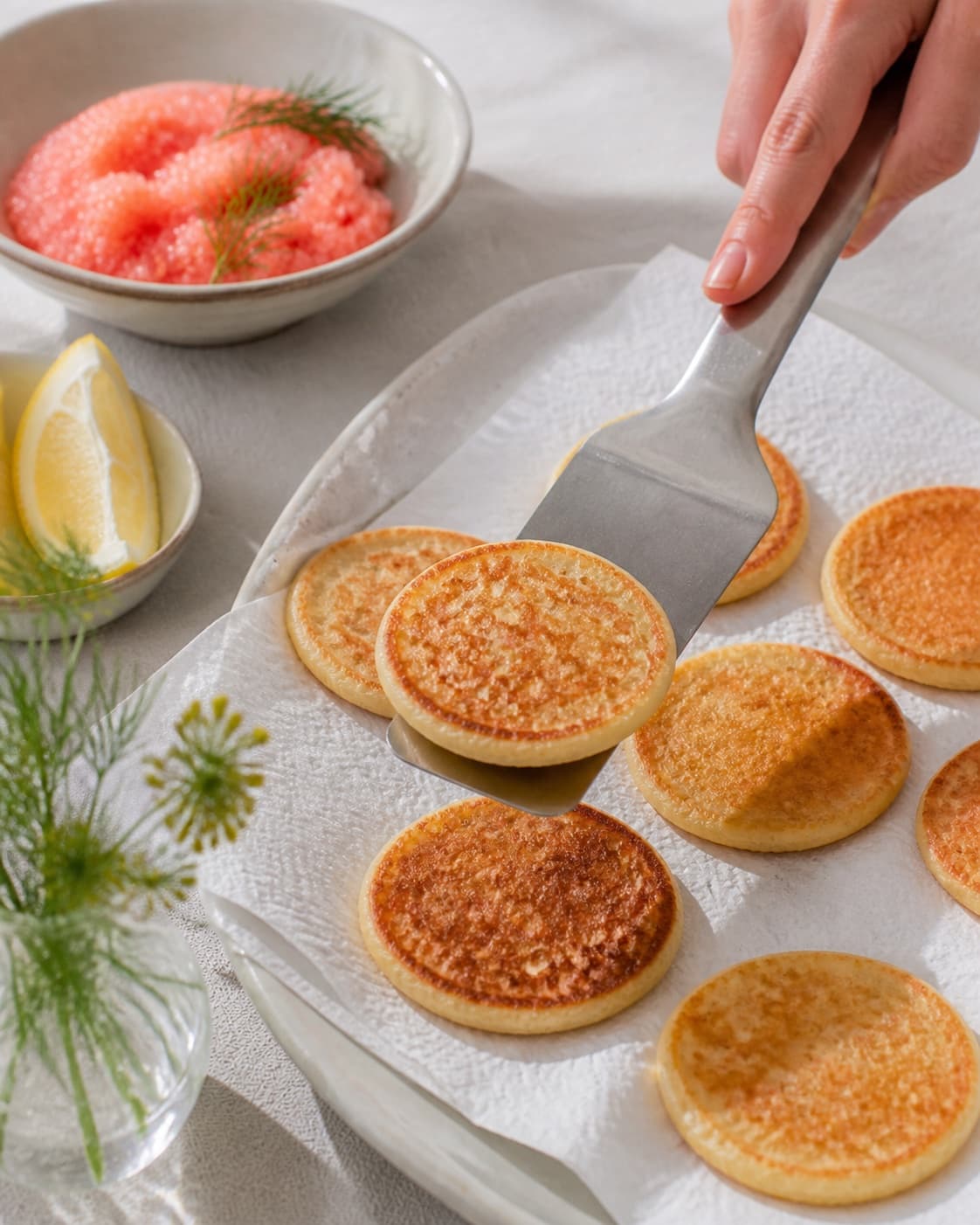 blinisene afdrypper sprød før citroncreme, stenbiderrogn og dild under tilberedningen af blinis med stenbiderrogn, dild og citroncreme