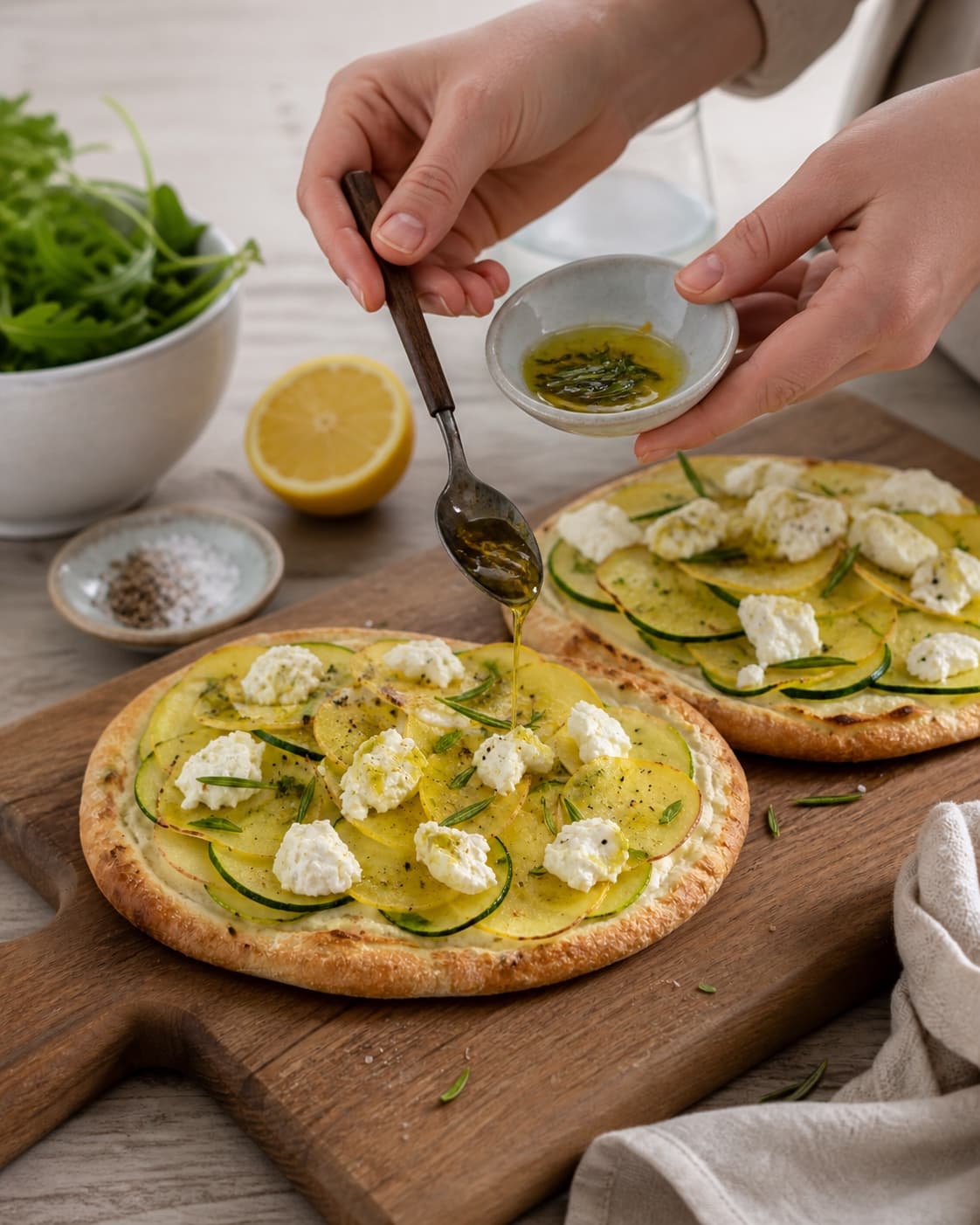 kartoffel-pitapizzaerne hviler før citronskal og rosmarinolie tilføjes under tilberedningen af pitapizza med kartoffel, rosmarin og citronricotta