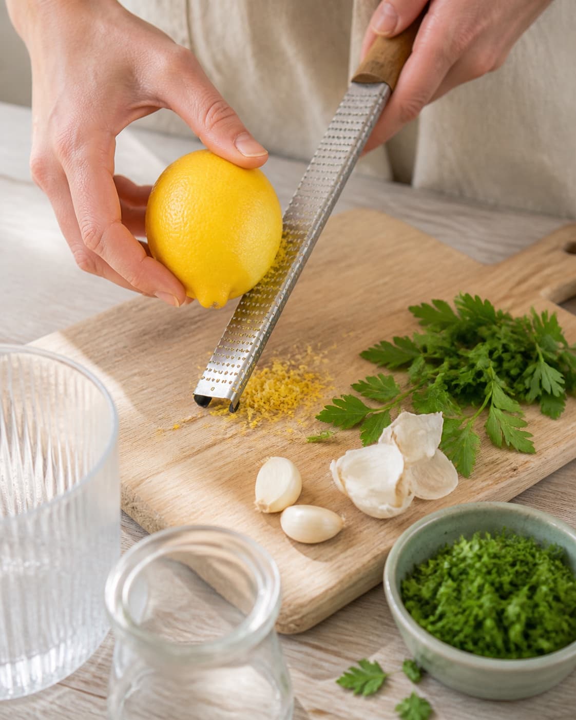 citronskal, hvidløg og persille renses ved siden af rene glas under tilberedningen af tahindressing med citron, yoghurt og spidskommen