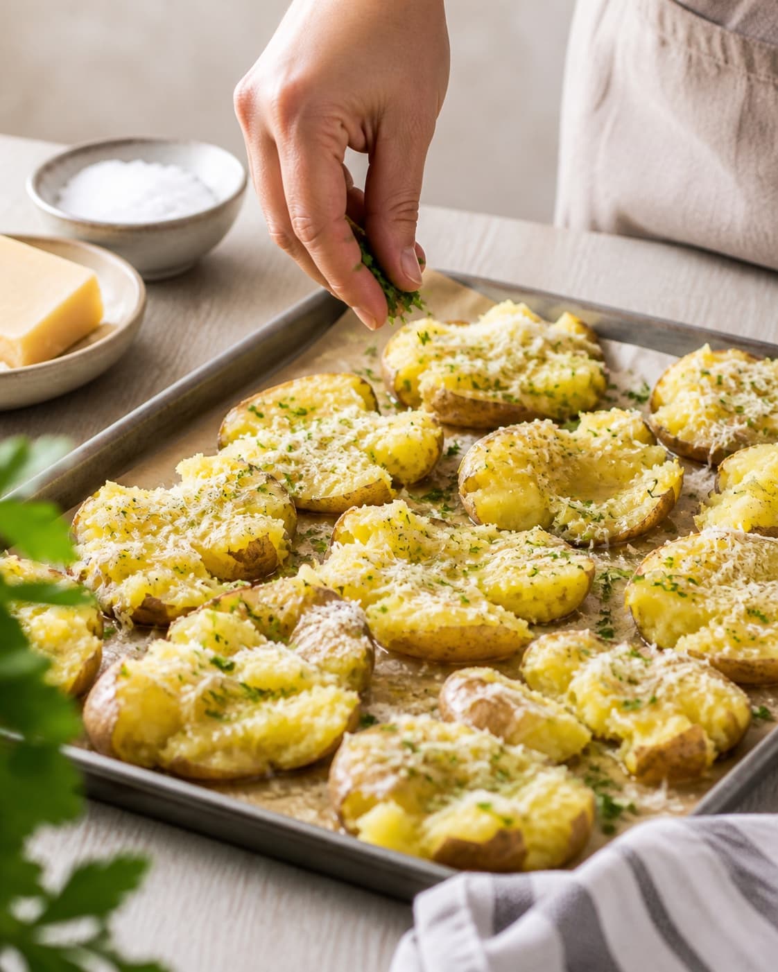 knuste kartofler med hvidløgssmør og parmesan being evenly seasoned before roasting under tilberedningen af knuste kartofler med hvidløgssmør og parmesan