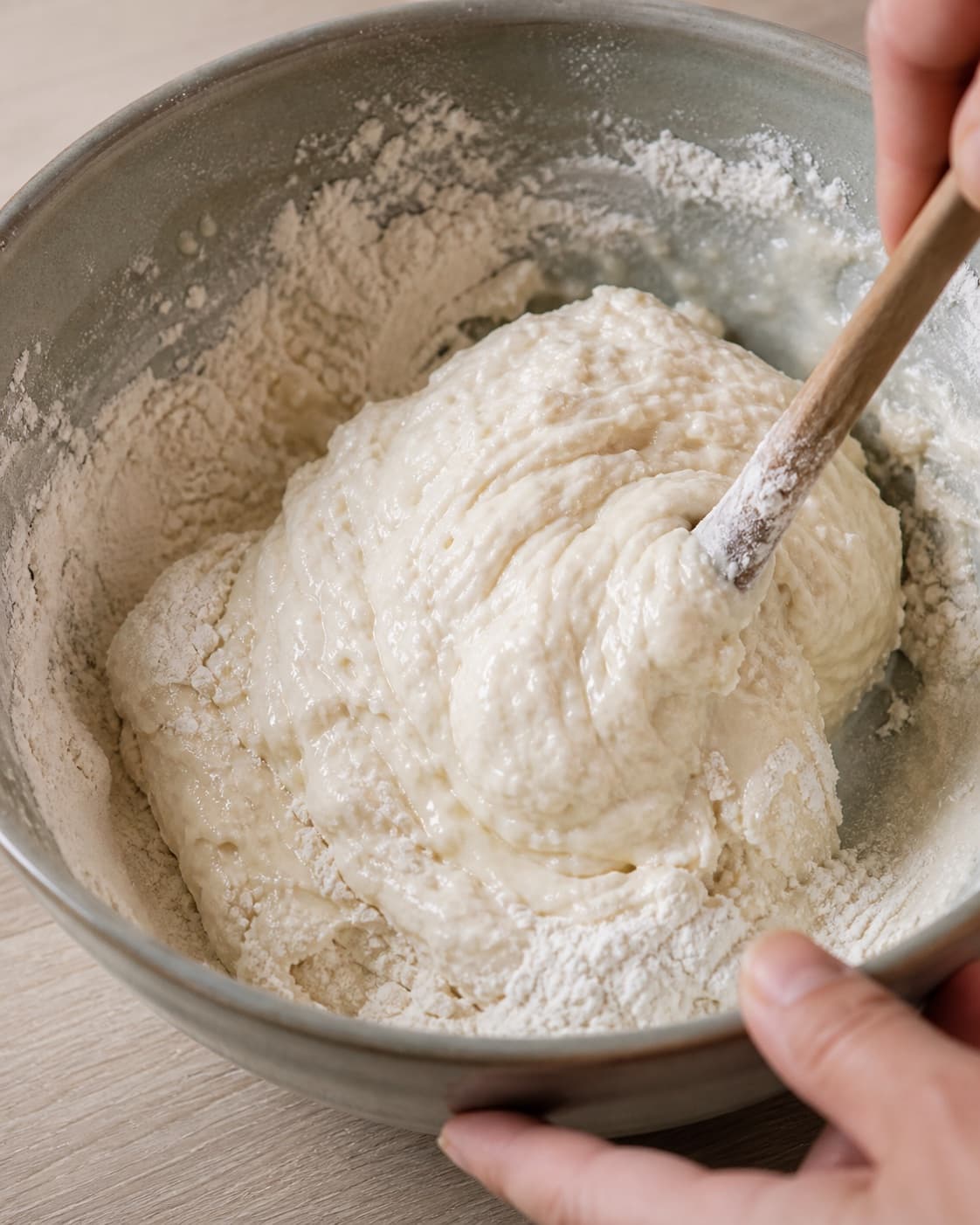 Close view of the moist dough for naanbrød på panden being mixed in a bowl with græsk yoghurt, hvedemel, lunkent vand, gær under tilberedningen af naanbrød på panden