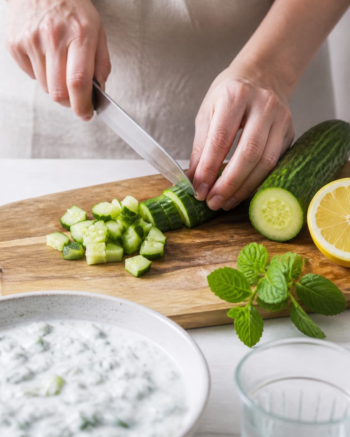 Ingredients for raita med agurk og mynte – indisk yoghurtdip being cut into even pieces under tilberedningen af raita med agurk og mynte – indisk yoghurtdip