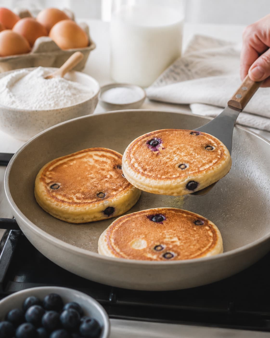 amerikanske blåbærpandekager frying to an even golden crust in a pan under tilberedningen af amerikanske blåbærpandekager